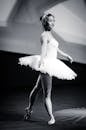 黑白照片中，一位优雅的女芭蕾舞演员正在舞台上表演