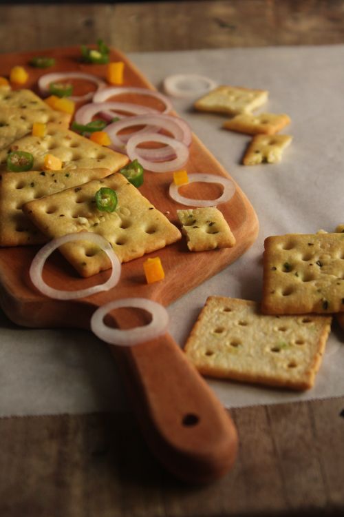 Free Assorted crackers with sliced onions and peppers on a rustic wooden board. Stock Photo
