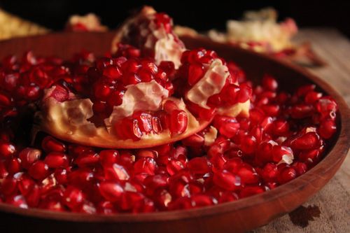 Free Vibrant close-up of fresh pomegranate seeds in a wooden bowl capturing their vivid color and texture. Stock Photo