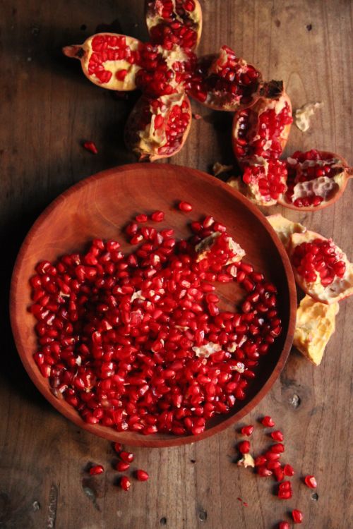 Free Top view of fresh, vibrant pomegranate seeds in a wooden bowl on rustic wooden table. Stock Photo