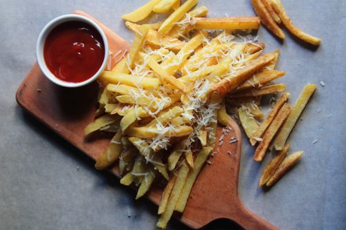 Free Crispy french fries topped with Parmesan cheese served with ketchup on a wooden board. Stock Photo