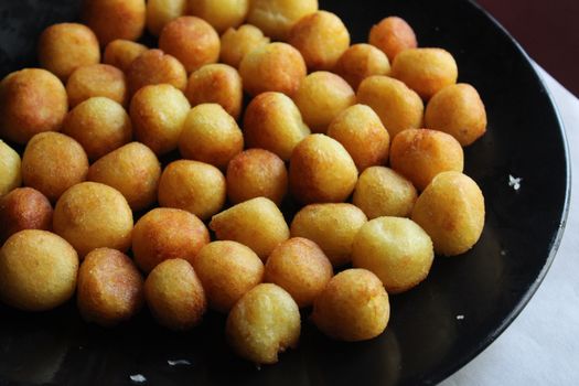 Delicious crispy golden potato balls served on a black plate, perfect for a savory snack.