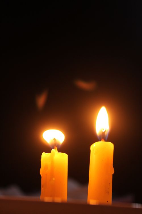Free Two glowing candles provide warmth and ambiance against a dark backdrop. Stock Photo