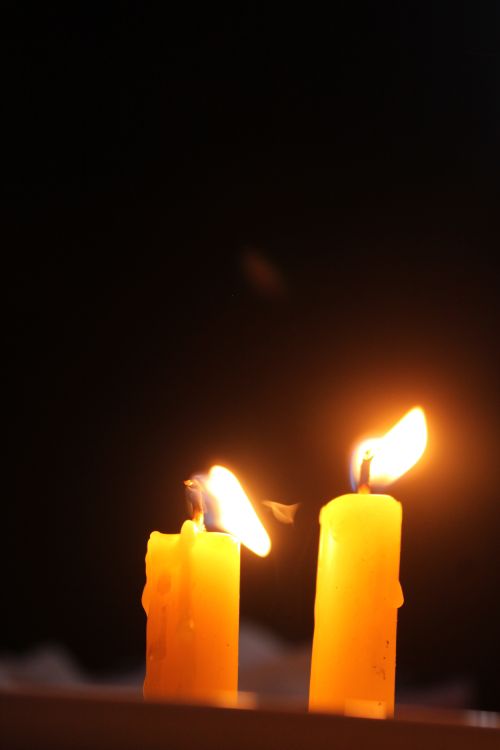 Free Two yellow candles burning against a dark background, conveying warmth and tranquility. Stock Photo