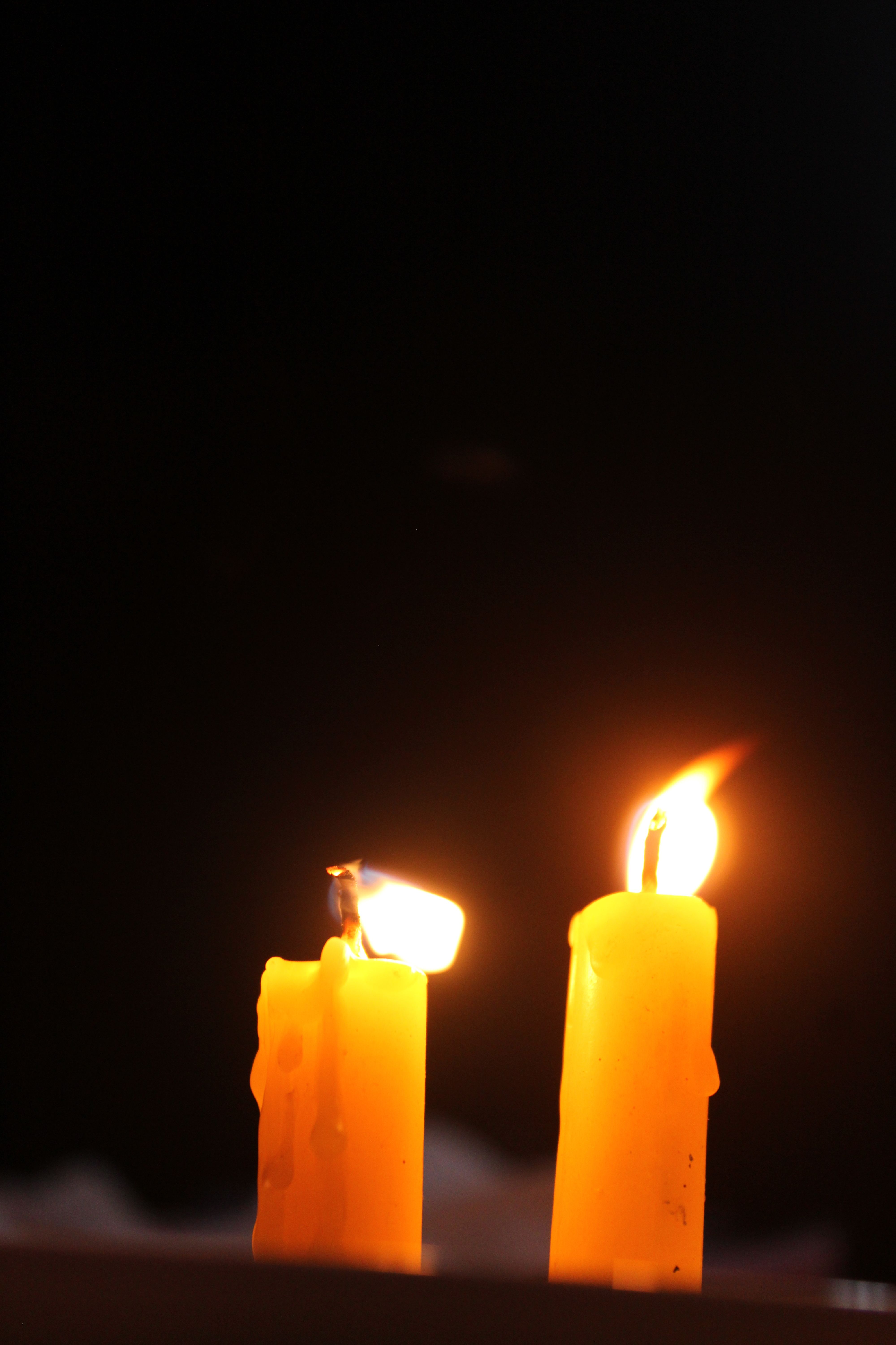 Two burning candles casting warm light against a dark background, creating a cozy ambiance.
