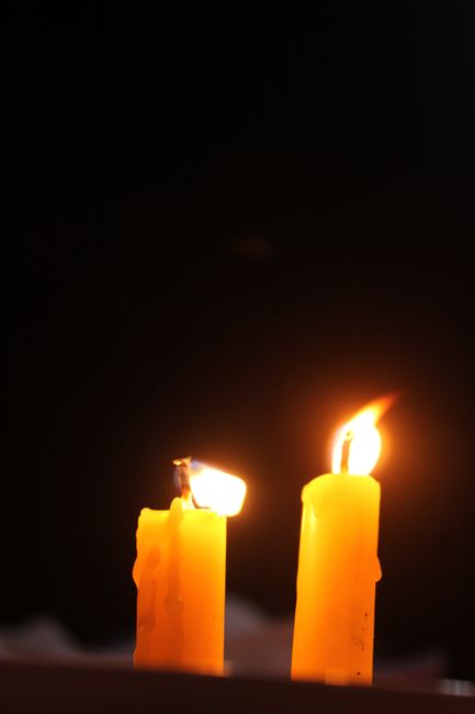 Two burning candles casting warm light against a dark background, creating a cozy ambiance.