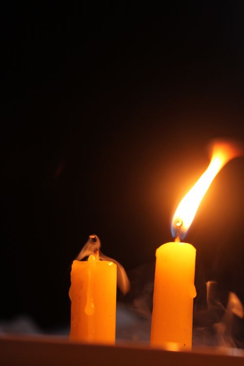 Free Close-up of a burning candle with wax drips against a dark background. Stock Photo