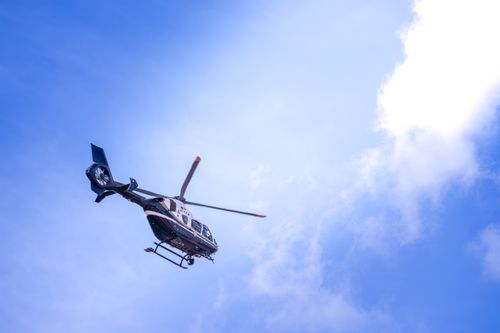Free A helicopter captured in flight against a bright blue sky with scattered clouds. Stock Photo
