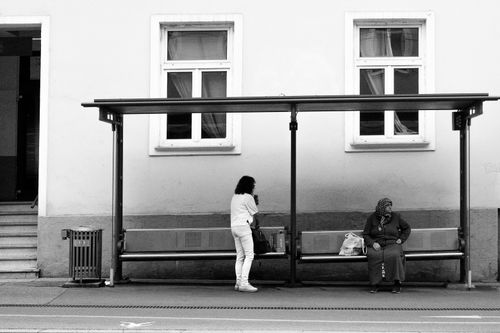 Free A candid street scene of two women at a bus stop in black and white. Stock Photo