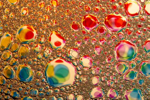 Free Creative macro shot of multicolored soap bubbles reflecting vivid colors in abstract patterns. Stock Photo