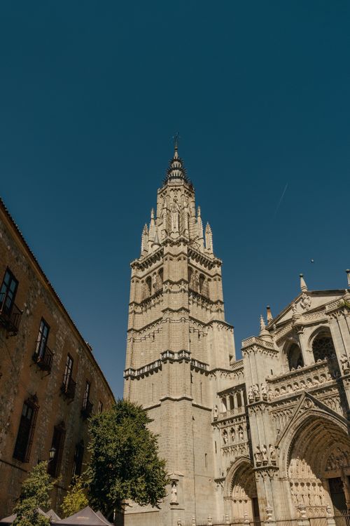 Free Gothic cathedral tower under a clear blue sky, featuring intricate architectural details. Stock Photo