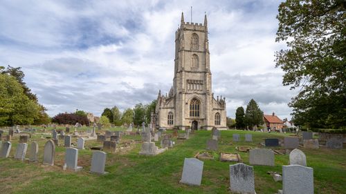 Free A picturesque rural church surrounded by an ancient cemetery under a cloudy sky. Stock Photo
