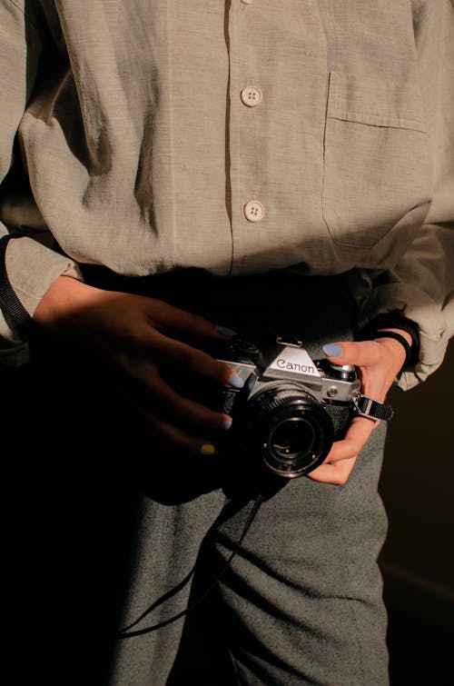 бесплатная человек, держащий черно серебряную камеру Стоковое фото