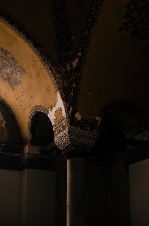 From below arched passage with pillar below ornamental dome ceiling in weathered medieval building corner