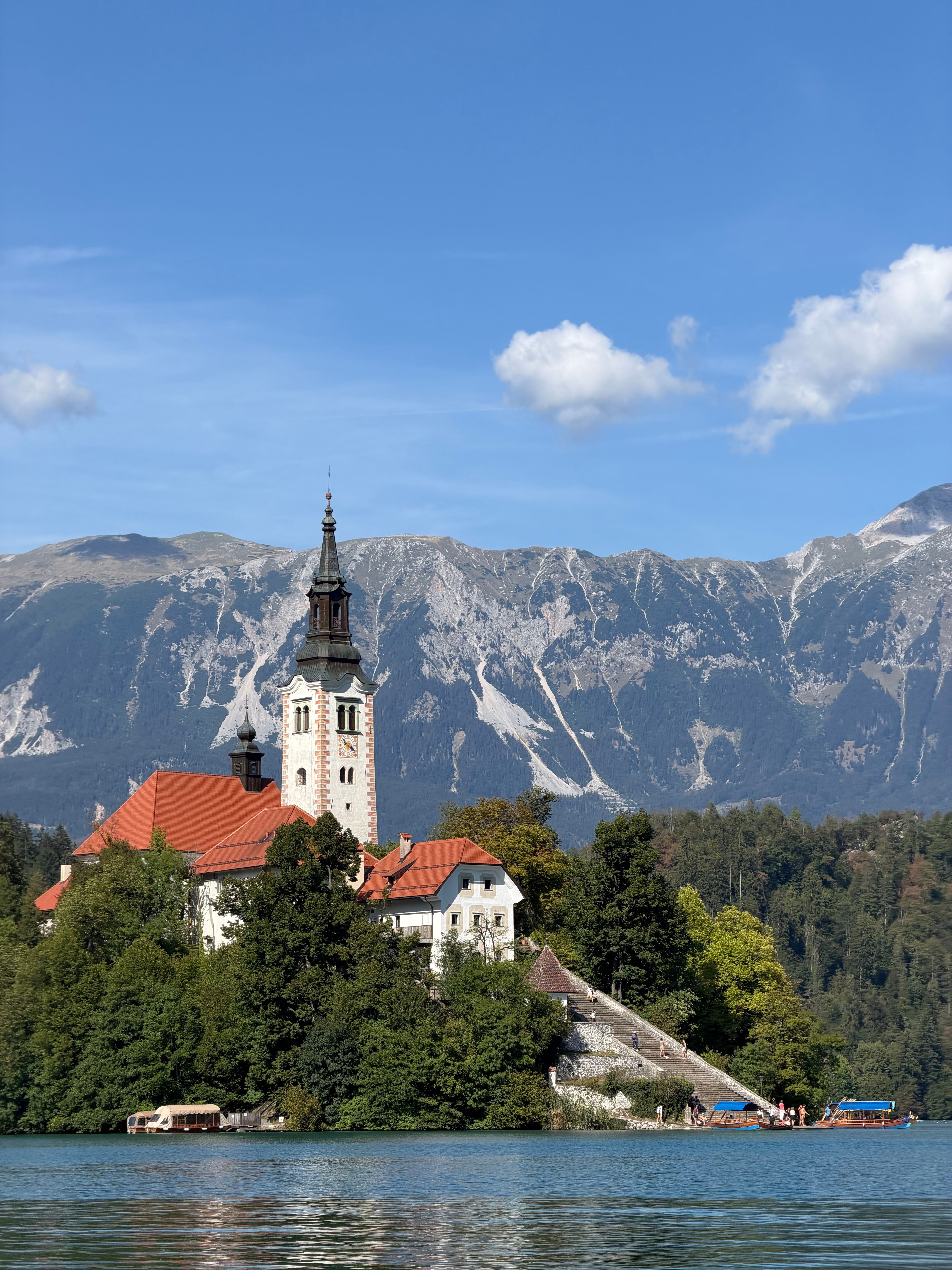 Picturesque Lake Bled island with church, surrounded by mountains under a clear sky.