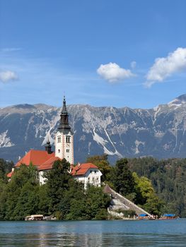 Picturesque Lake Bled island with church, surrounded by mountains under a clear sky.