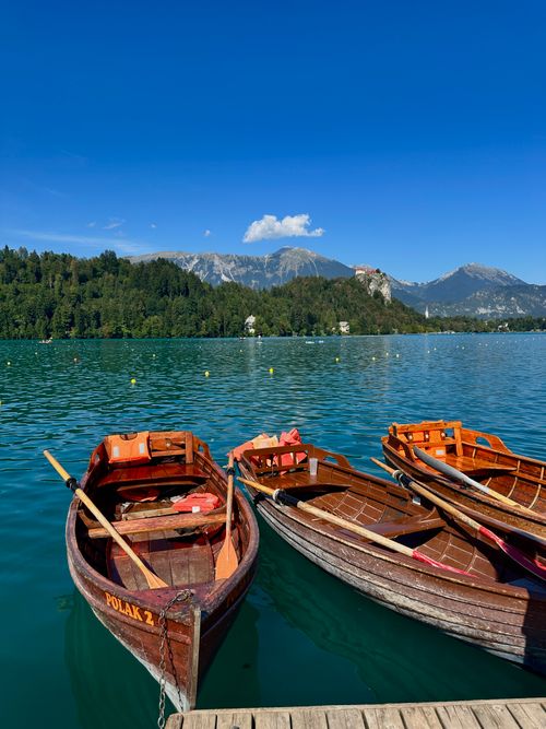Free Wooden boats docked on Lake Bled with scenic mountains in Slovenia. Stock Photo