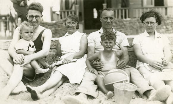 A sepia-toned vintage family photo at a beach, featuring adults and children in a relaxed setting.