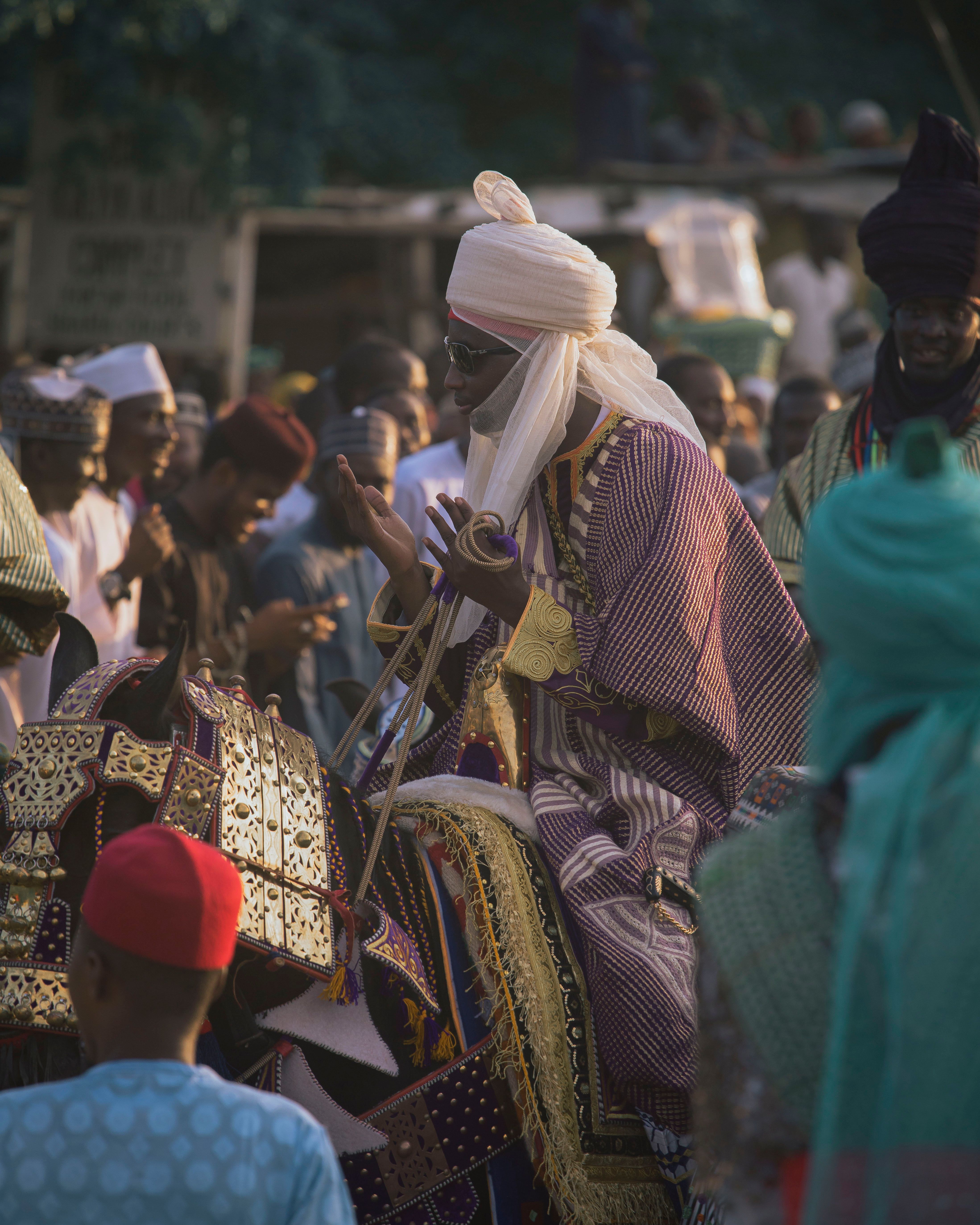 A majestic parade featuring a royal figure in traditional attire on horseback among a diverse crowd.