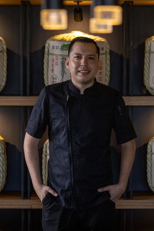 Free Portrait of a chef in black standing in a Japanese restaurant setting. Stock Photo