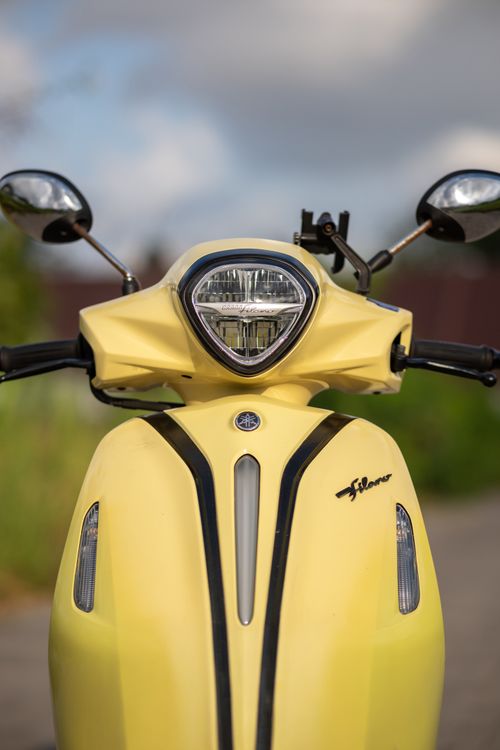 Free Close-up of a yellow scooter with shiny mirrors and blue sky background. Stock Photo