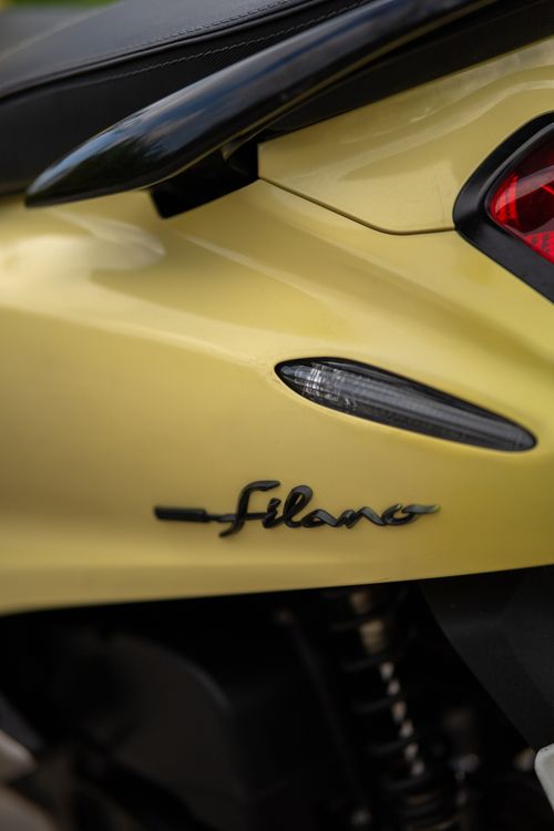 Free Detailed view of the rear section of a yellow motorcycle featuring the Filano logo and sleek design. Stock Photo