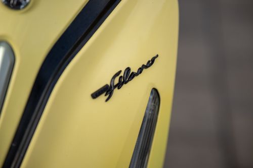 Free Macro shot of the Vespa Scootera logo on a sleek, yellow scooter panel. Stock Photo