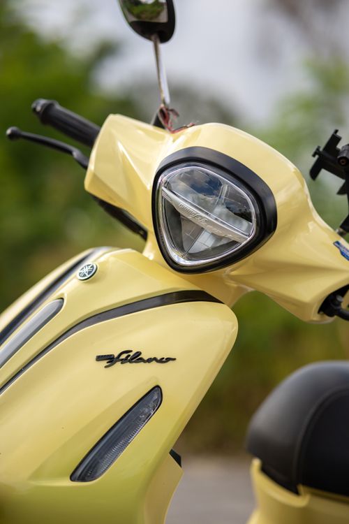 Free Vibrant close-up of a yellow scooter's front, highlighting the headlight and logo. Stock Photo