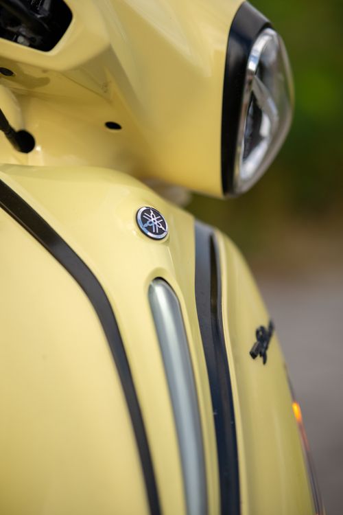 Free Detailed view of a yellow scooter's headlight and logo in focus. Stock Photo
