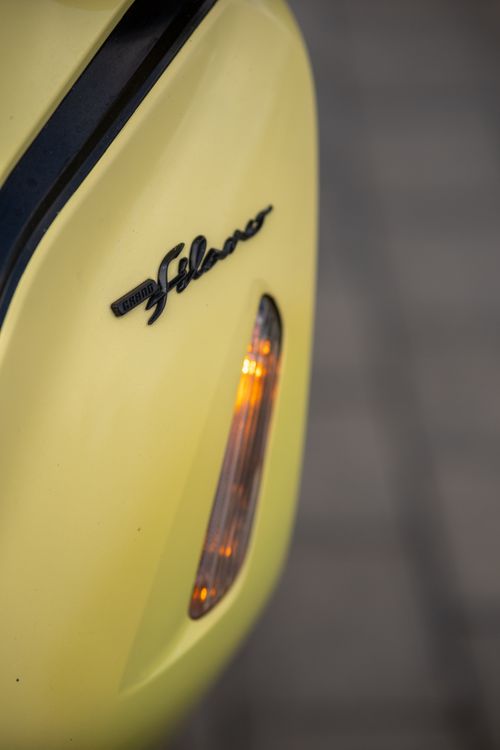 Free Detailed view of a yellow Vespa scooter with emblem and side light visible. Stock Photo