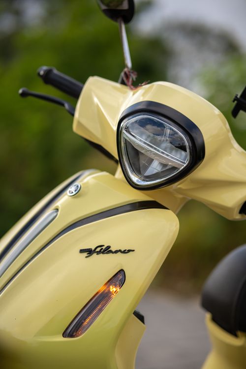 Free A stylish yellow scooter with headlight focus, emblem, and vibrant outdoor setting. Stock Photo