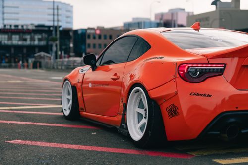 Free Dynamic side view of a modified orange sports car parked in an urban environment, showcasing custom design. Stock Photo