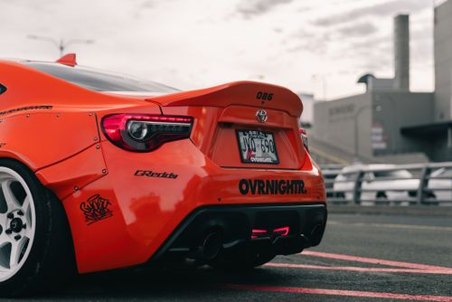 Free Close-up of an orange sports car with custom design and license plate in urban setting. Stock Photo