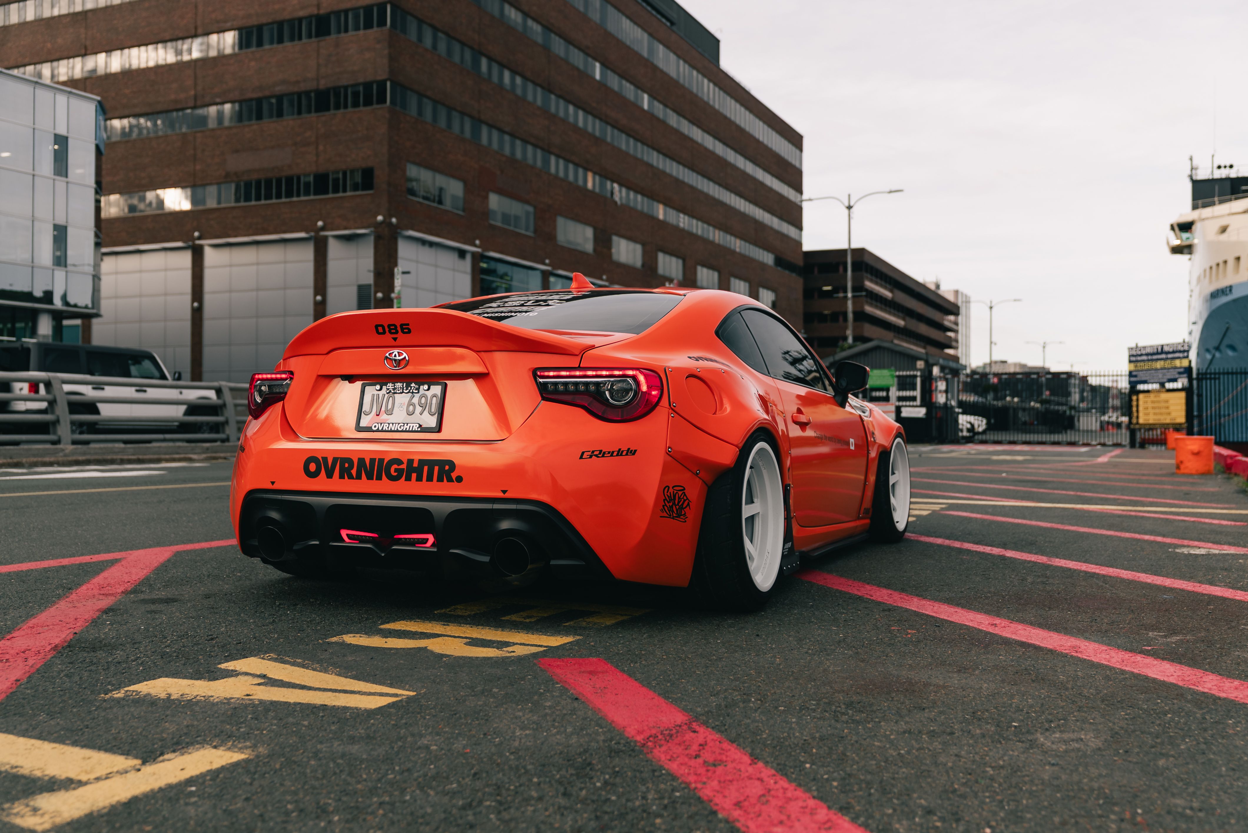 Bright orange custom car parked on an urban street, showcasing tuning details and sports aesthetics.