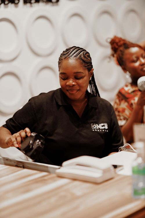 Free A woman in a cafe uniform serving coffee while a singer performs in the background. Stock Photo