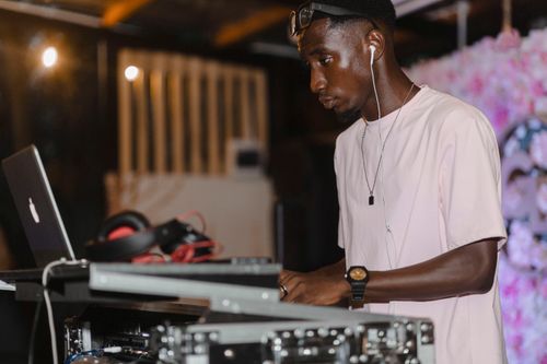 Free A DJ skillfully mixes music using a laptop and headphones at an indoor event. Stock Photo