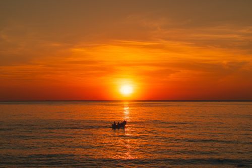 Free A tranquil sunrise above the sea with a silhouetted boat in Quảng Trị, Vietnam. Stock Photo