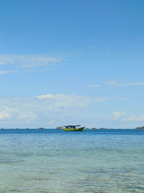 Free A tranquil view of a fishing boat on a clear blue ocean under a bright sky. Stock Photo