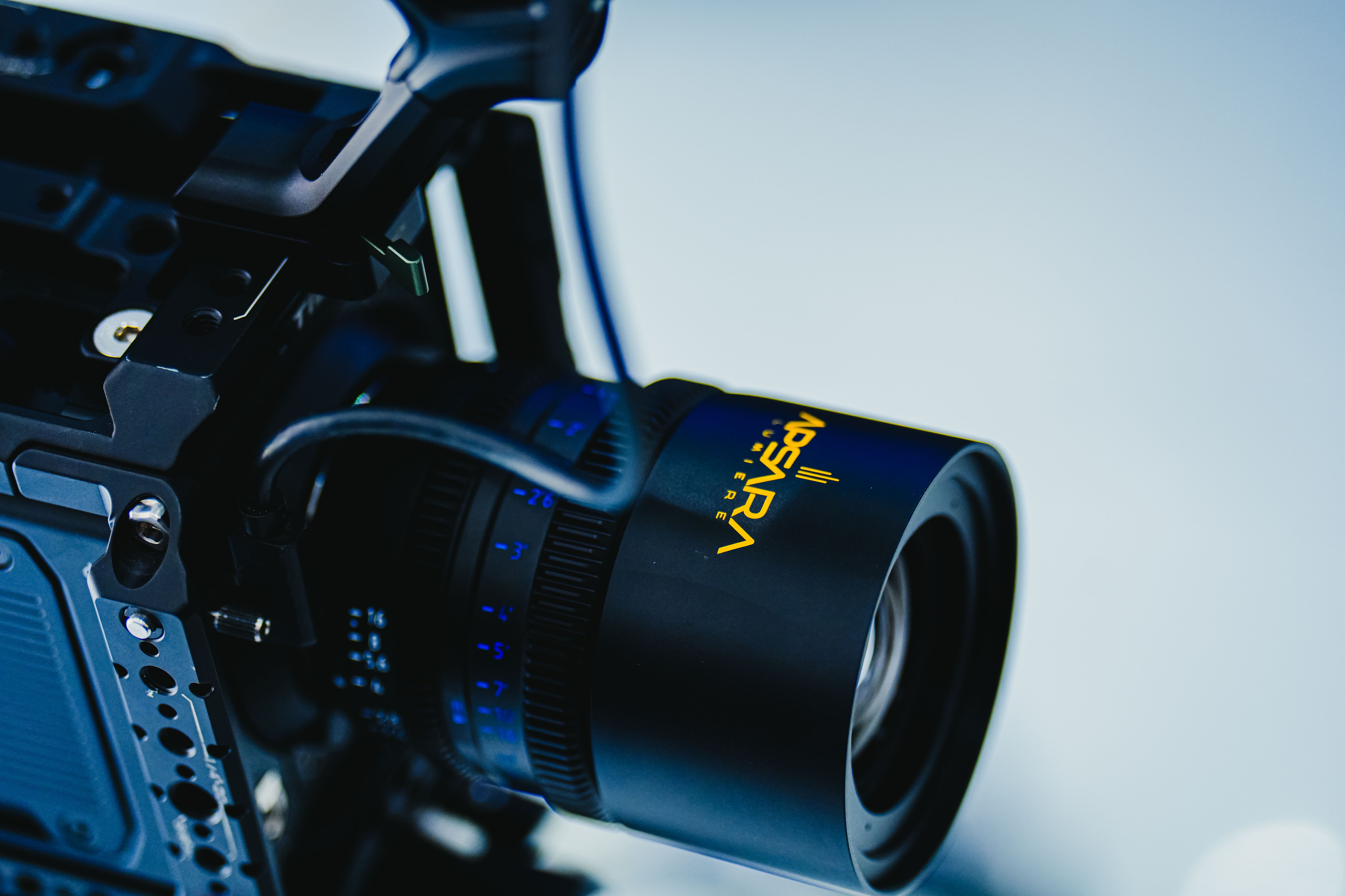 Detailed image of a professional cinema camera lens with blue highlights on a gradient background.