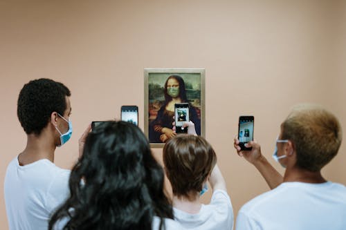 Free People Taking Picture of A Painting Of Mona LIsa With Face Mask Stock Photo