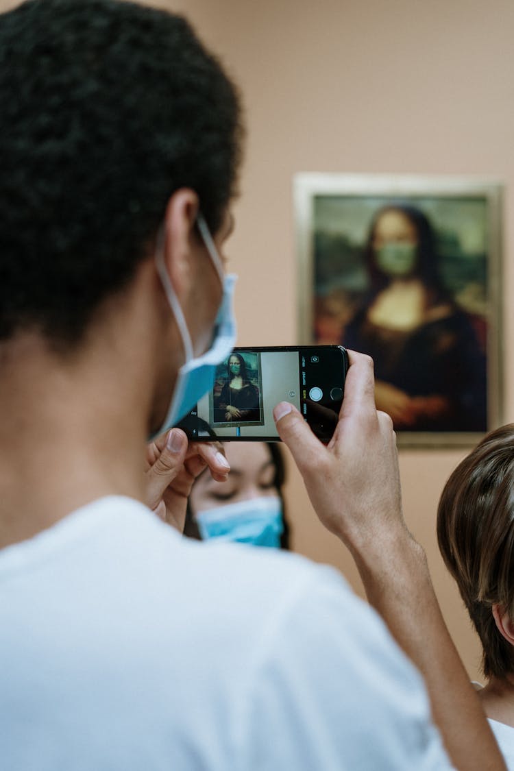 Man Taking Picture Of A Painting Of Mona Lisa Wearing Face Mask