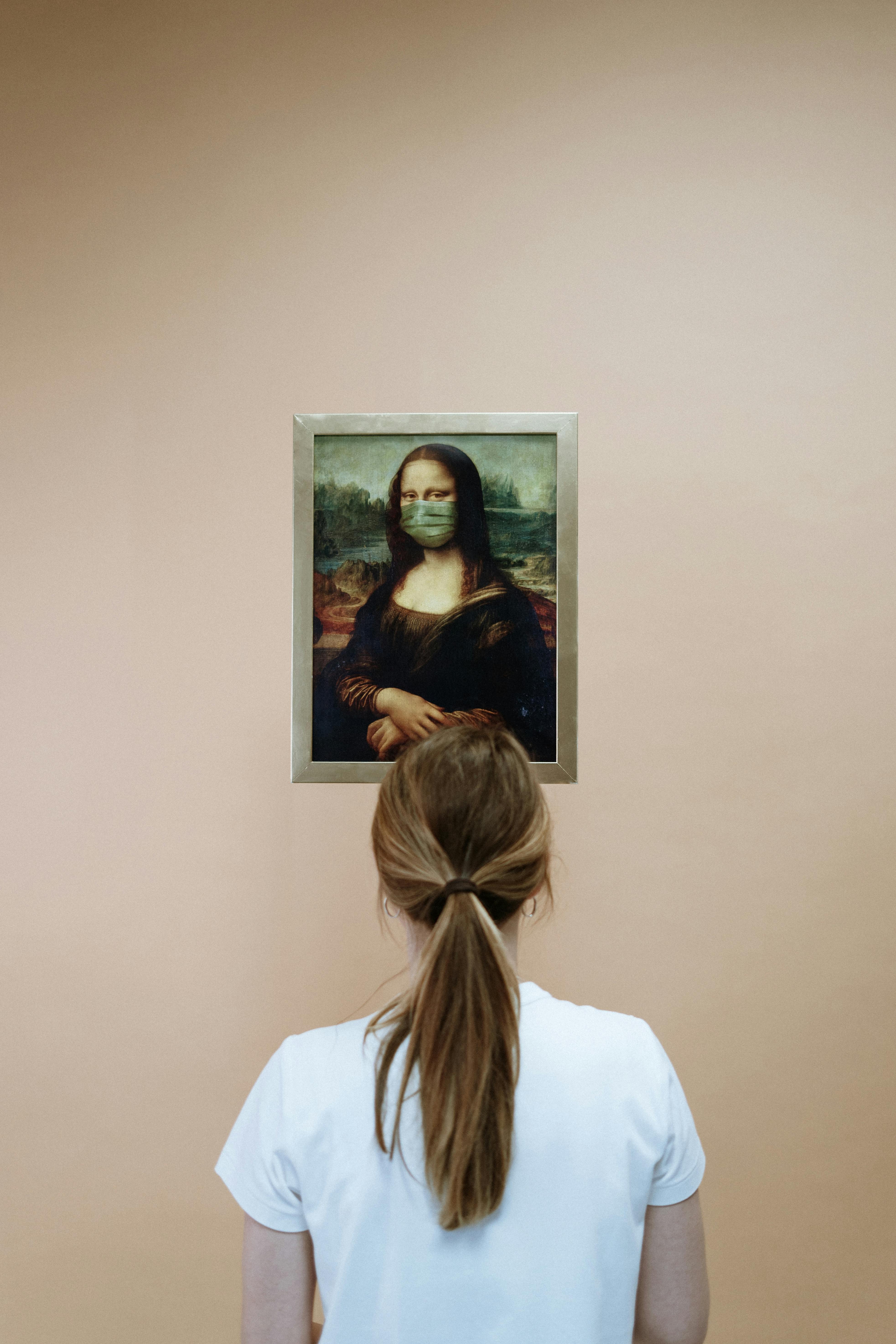 Woman In White Shirt Looking At A Painting Of Mona Lisa With Face