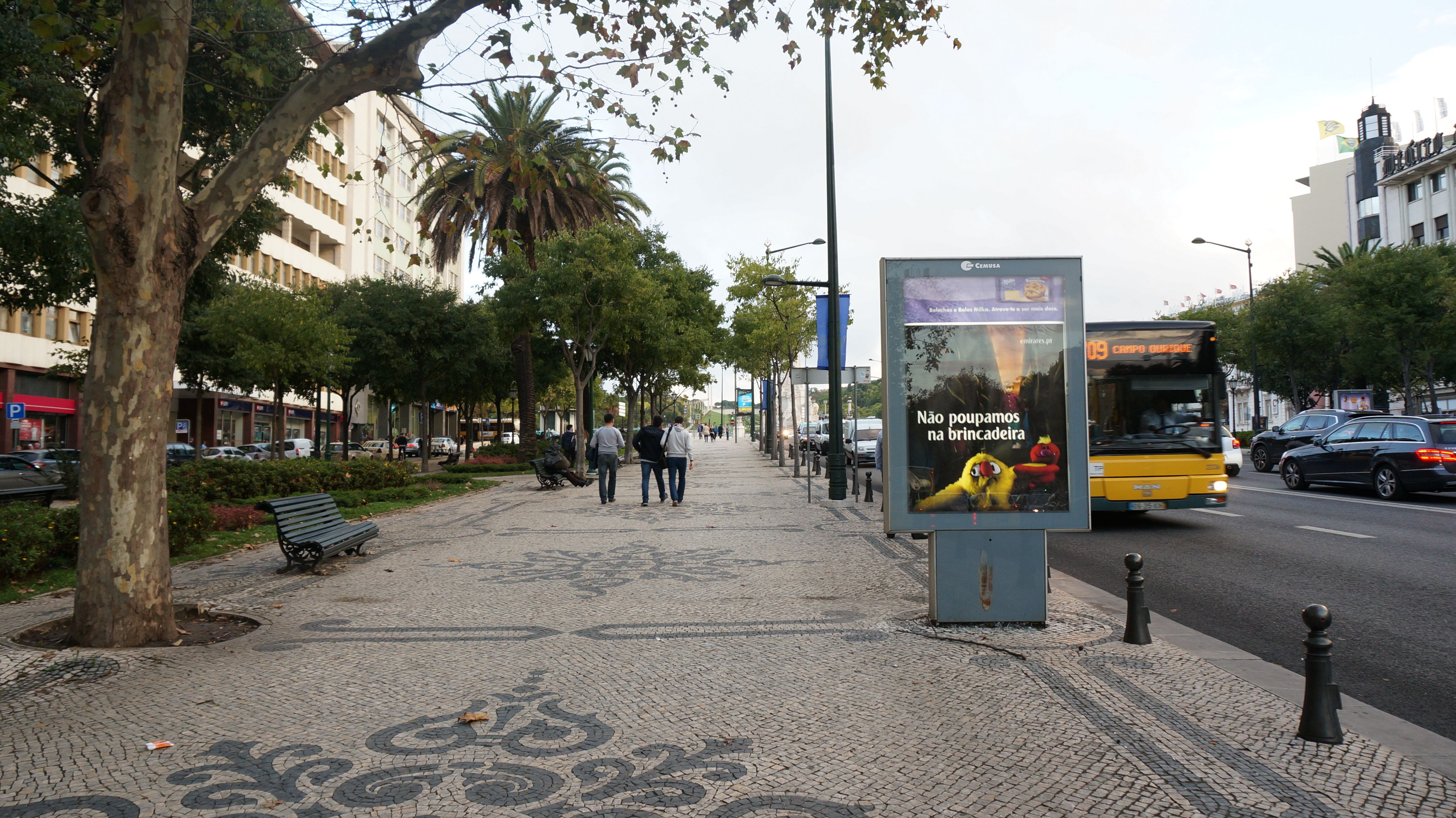 A lively street in Lisbon, Portugal with people walking and a city bus passing by.
