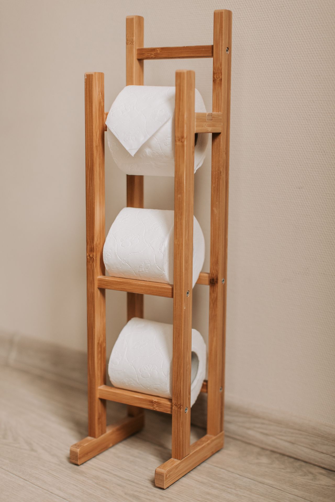 Wooden rack holding three rolls of toilet paper in a bright room