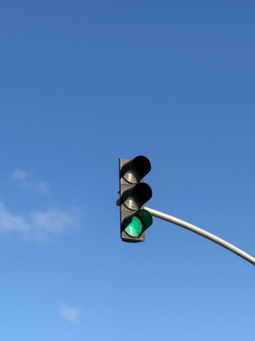 Free A green traffic light illuminated under a clear blue sky, symbolizing go and positivity. Stock Photo