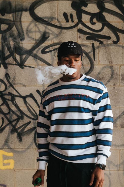 Free Young man vaping against a graffiti wall. Street style with smoky effect, perfect for urban lifestyle themes. Stock Photo