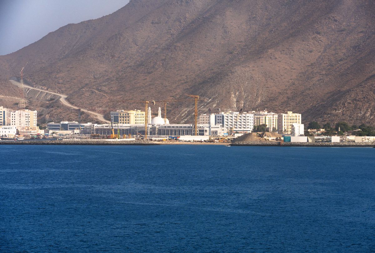 Khorfakkan waterfront buildings and mosque on the deep blue sea, with the Hajar mountains behind