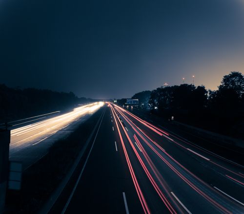 Free Long exposure photo capturing vehicle light trails on a highway at night with a serene night sky. Stock Photo