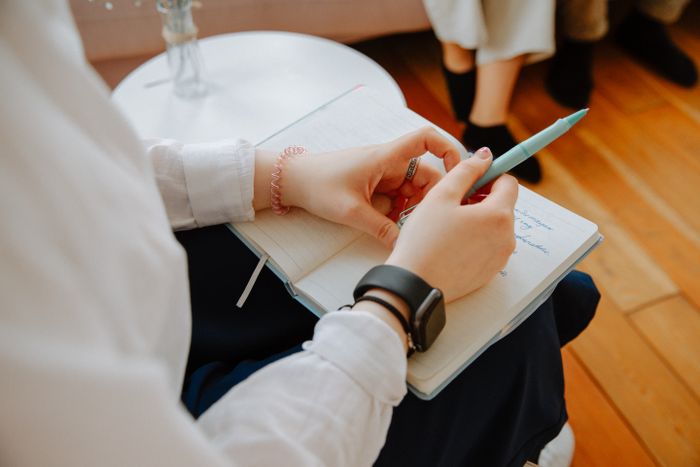 Close-up of a wellness professional taking notes during a client conversation