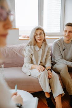 A couple engaged in a discussion with their therapist during a counseling session, indoors.